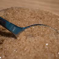 A bowl of brown sugar with a measuring spoon