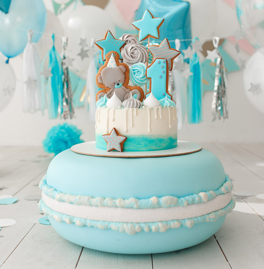 A blue macaroon inspired cake covered in fondant icing and decorated with shapes and numbers made out of iced biscuits 
