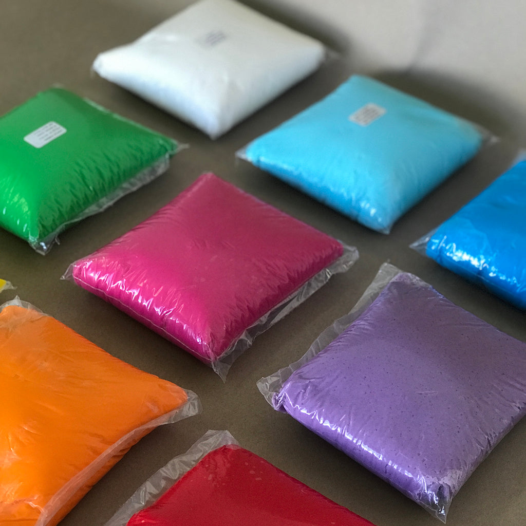 Packets of white, light blue, dark blue, green, pink, purple, orange, and red fondant / plastic icing 